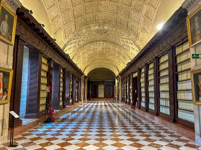 a long hallway with a checkered floor and paintings on the walls